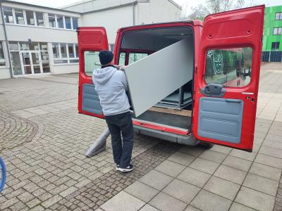 Die gespendeten Tische werden aus dem Schulbus ausgeladen